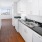 Dog Friendly Apartments in San Francisco CA - Trinity Place at 1190 - Aisle-Style Kitchen with Black Countertops, White Cabinets, Wood-Style Flooring, and White Appliances